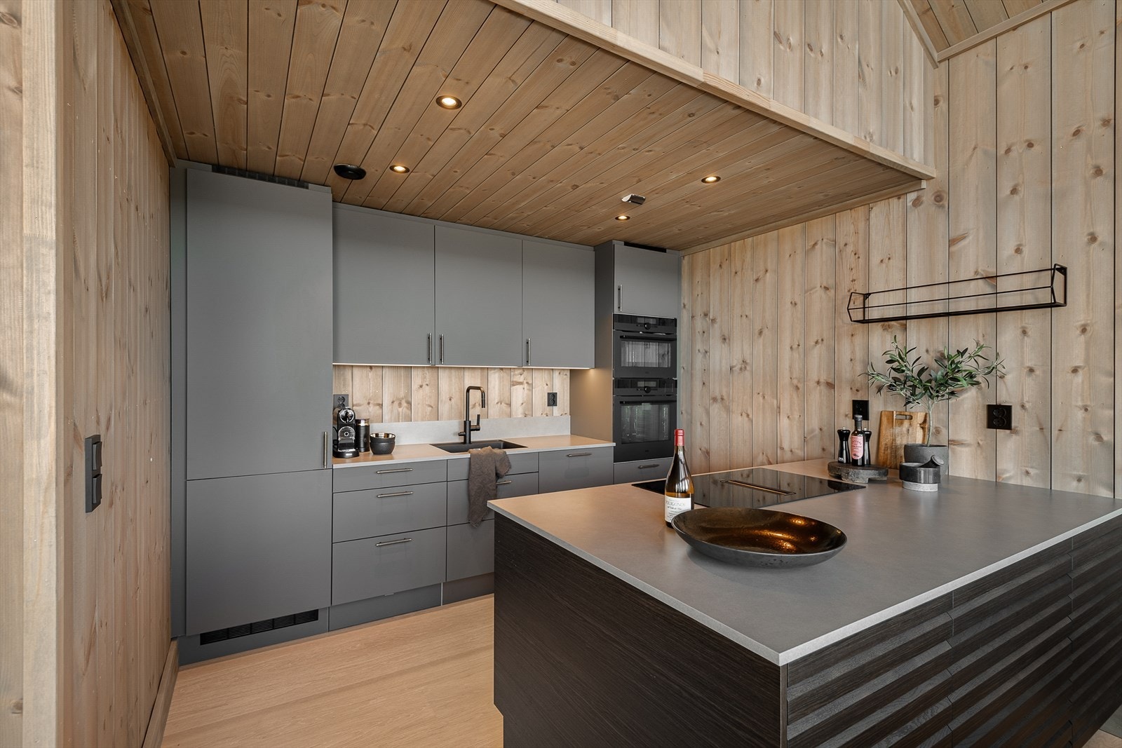 Kjøkkenet er innredet i en praktisk form med godt med skap- og oppbevaringsplass. Innredningen er i lekker grå utførelse kombinert med mørere spilefronter i tre på kjøkkenøyen. Som gir et moderne og stilrent uttrykk! Galleribilde