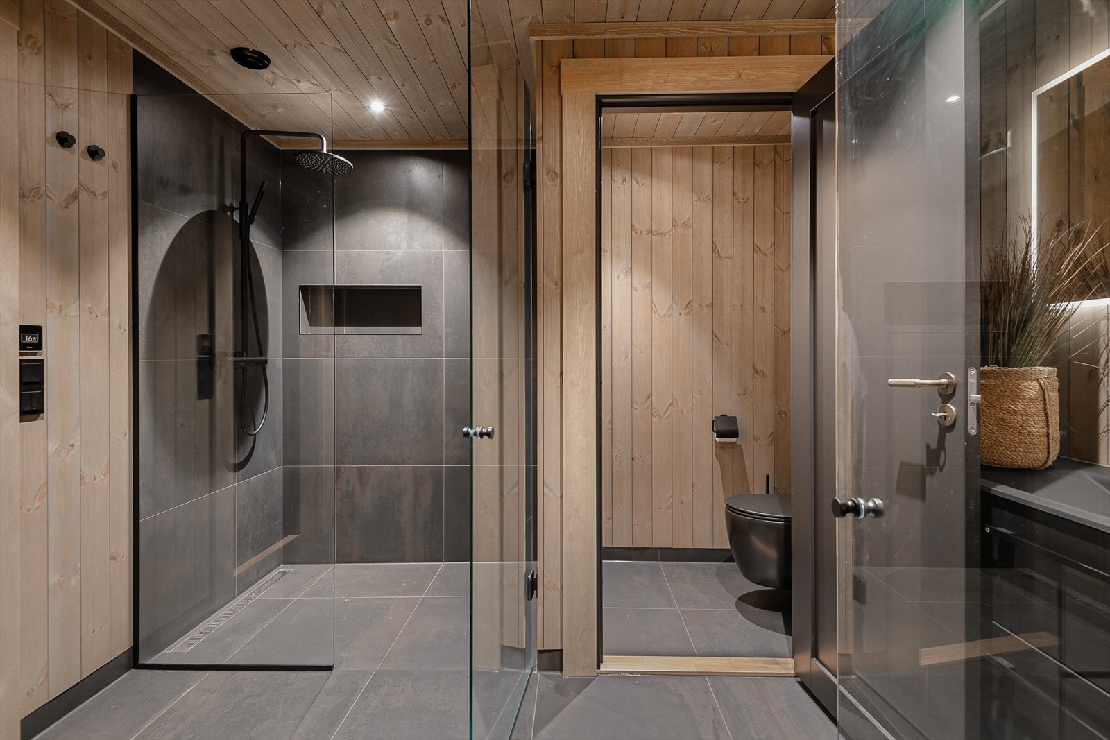 Baderommet som er beliggende i underetasjen er med fliselagte overflater på vegger og gulv. Videre er rommet utstyrt med baderomsinnredning med servant, speil med tilhørende belysning og dusjvegger. Galleribilde