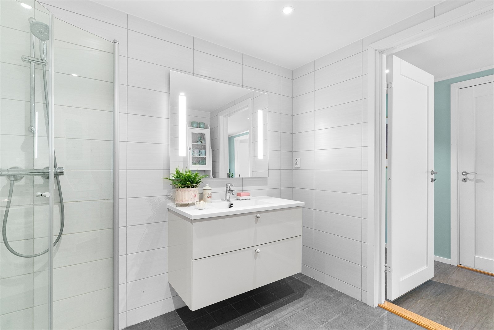 Badet er lunt og delikat med flislagte overflater. Belysningen er god, både fra speilet og fra downlights i taket. Galleribilde