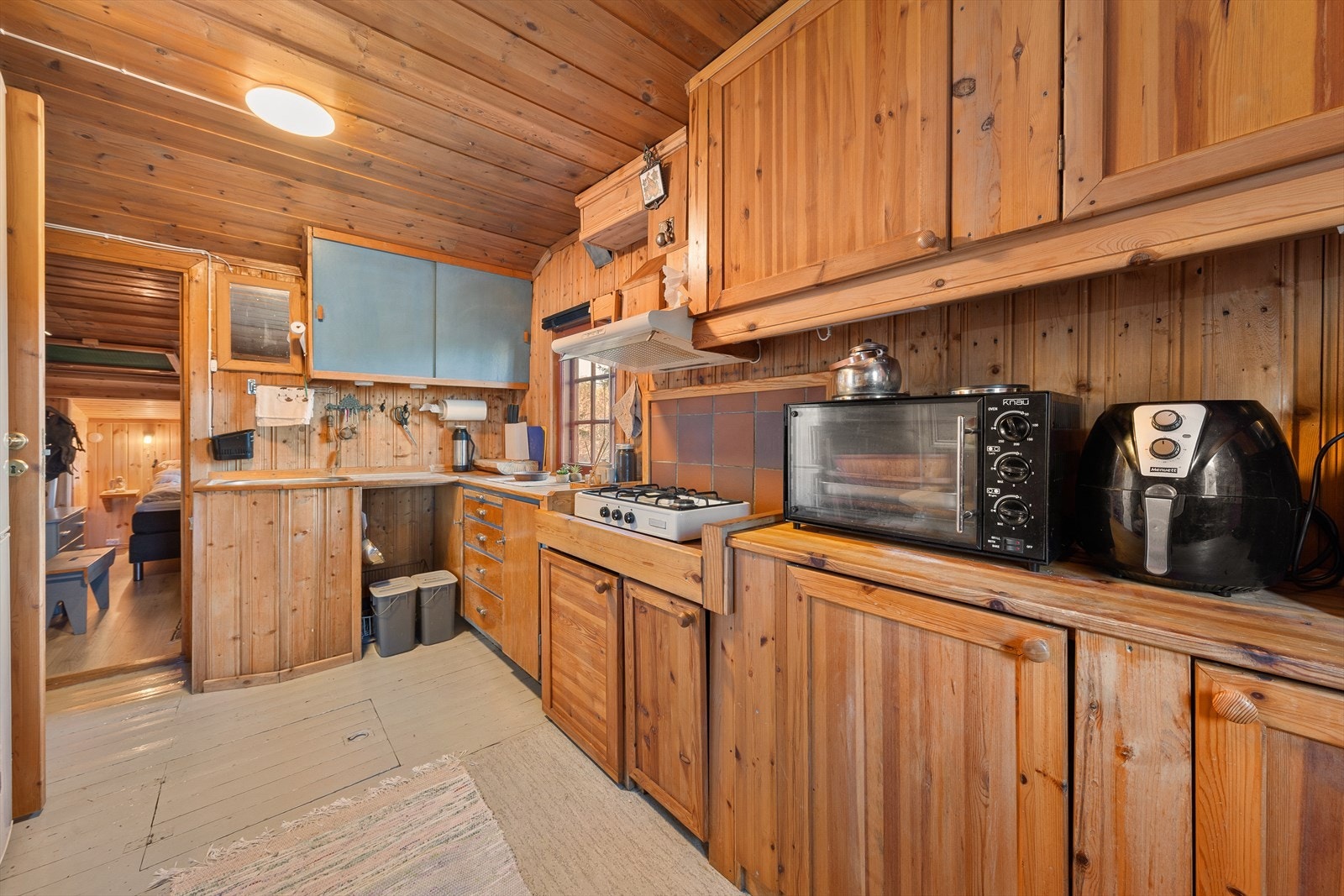 Hytta har et funksjonelt kjøkken med rikelig oppbevaringsplass i solide trefronter. Her finner du gasskomfyr, benkeplass til matlaging og plass til nødvendige kjøkkenapparater. Galleribilde