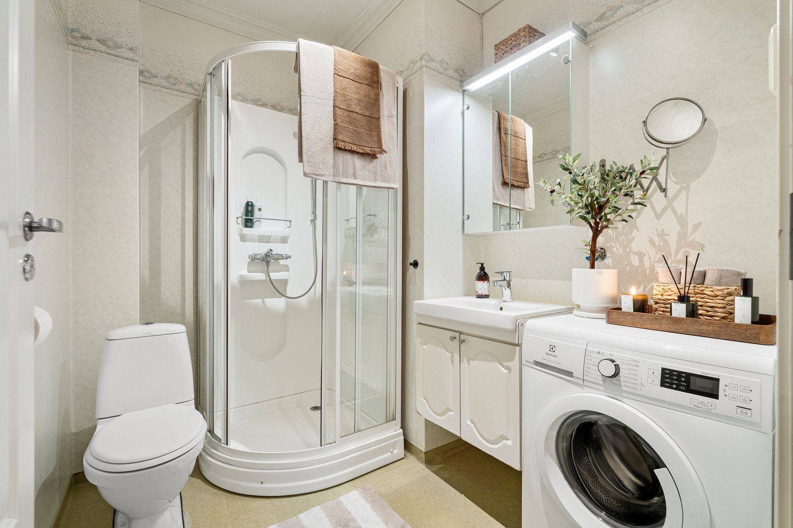 Lyst og funksjonelt bad, innredet med dusjkabinett, servant og toalett. Galleribilde