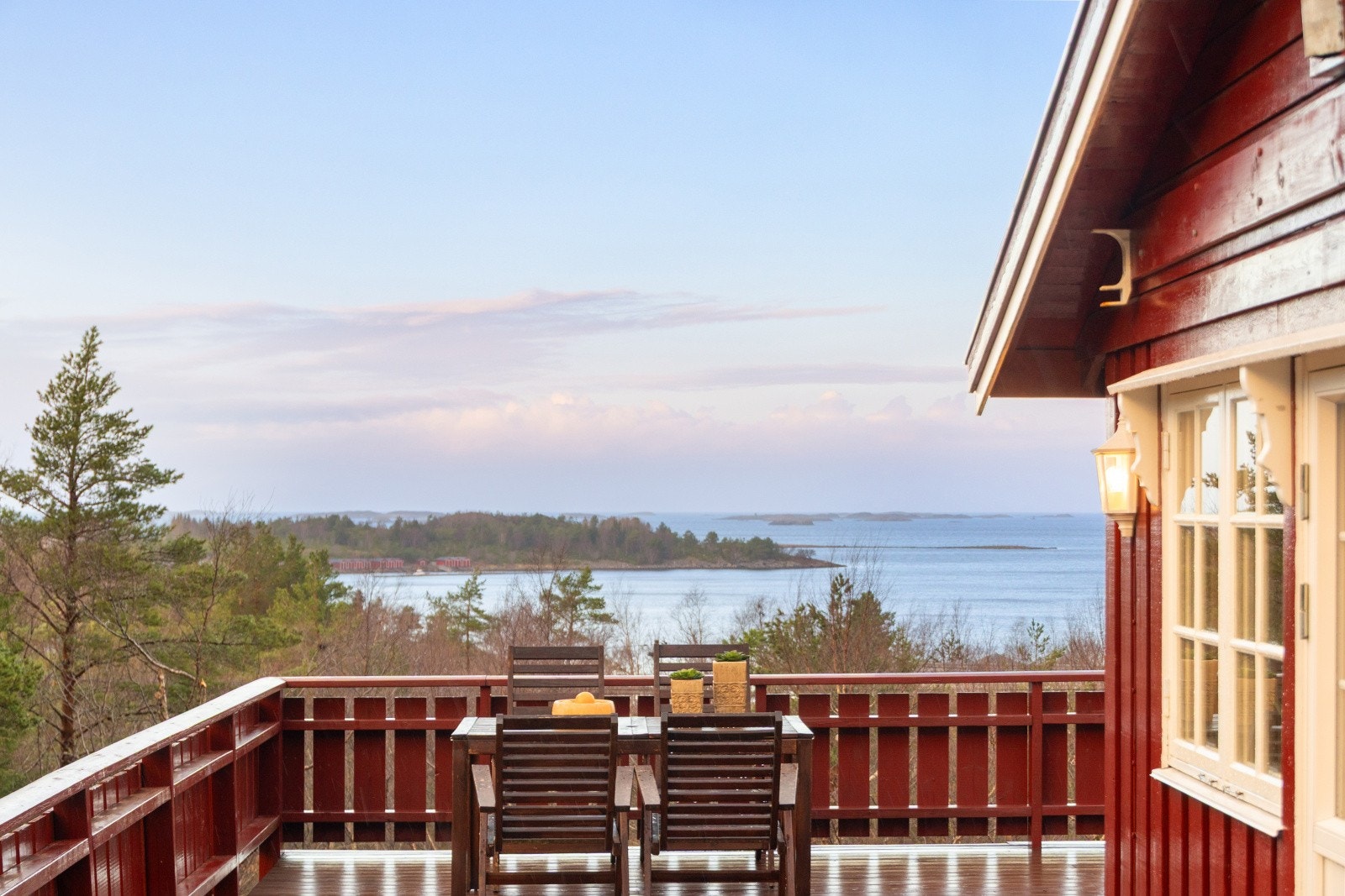 Rødmalte fasader og en stor terrasse gir en innbydende ramme rundt fritidsboligen. Galleribilde