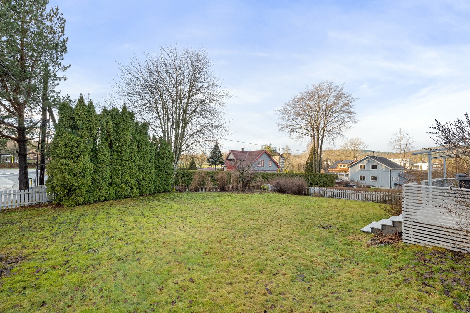 Boligen har en stor og flat tomt bestående av grønn hage med beplantning. Galleribilde
