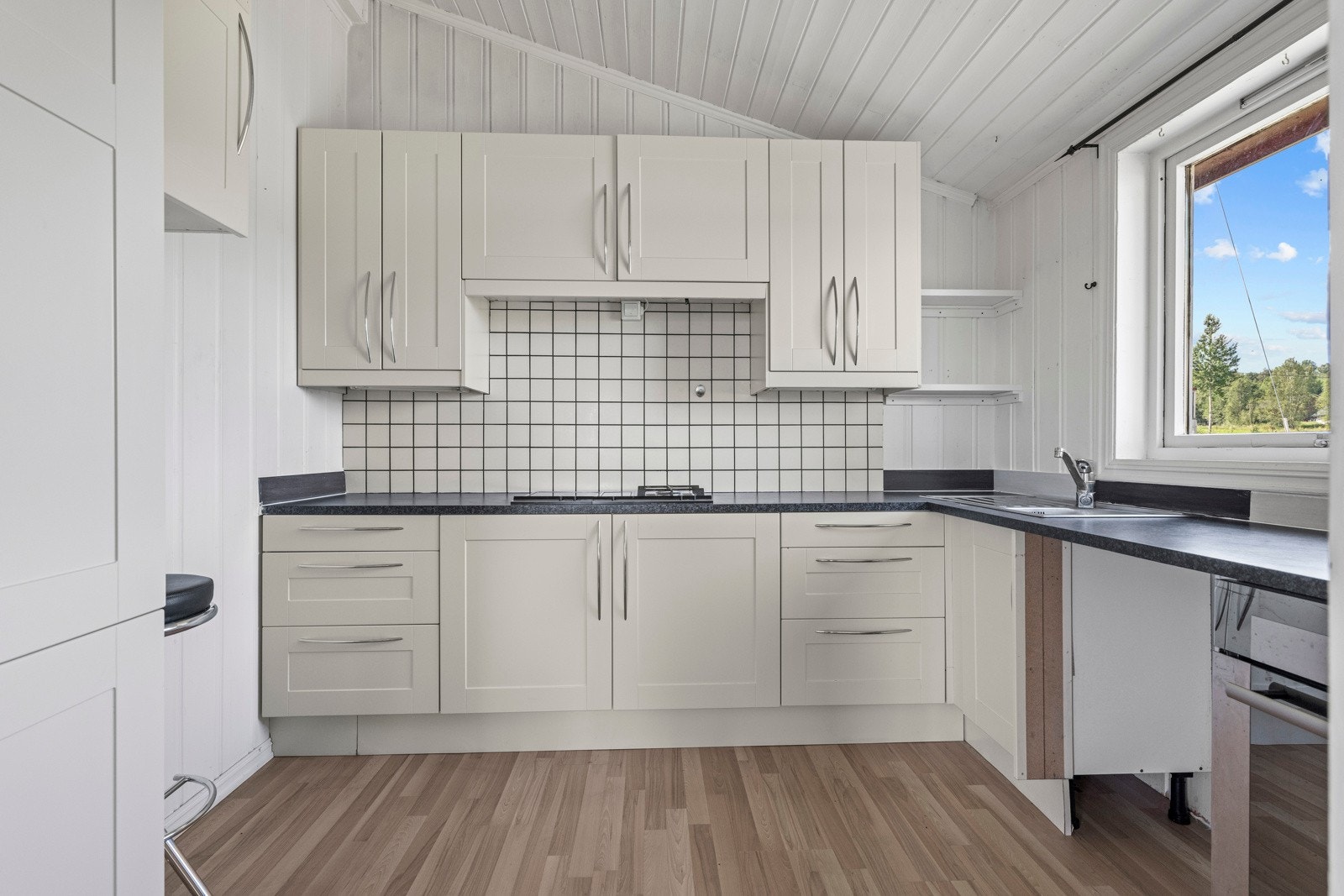 Lyst og sjarmerende kjøkken med innredning med profilerte fonter og benkeplate av laminat. Galleribilde