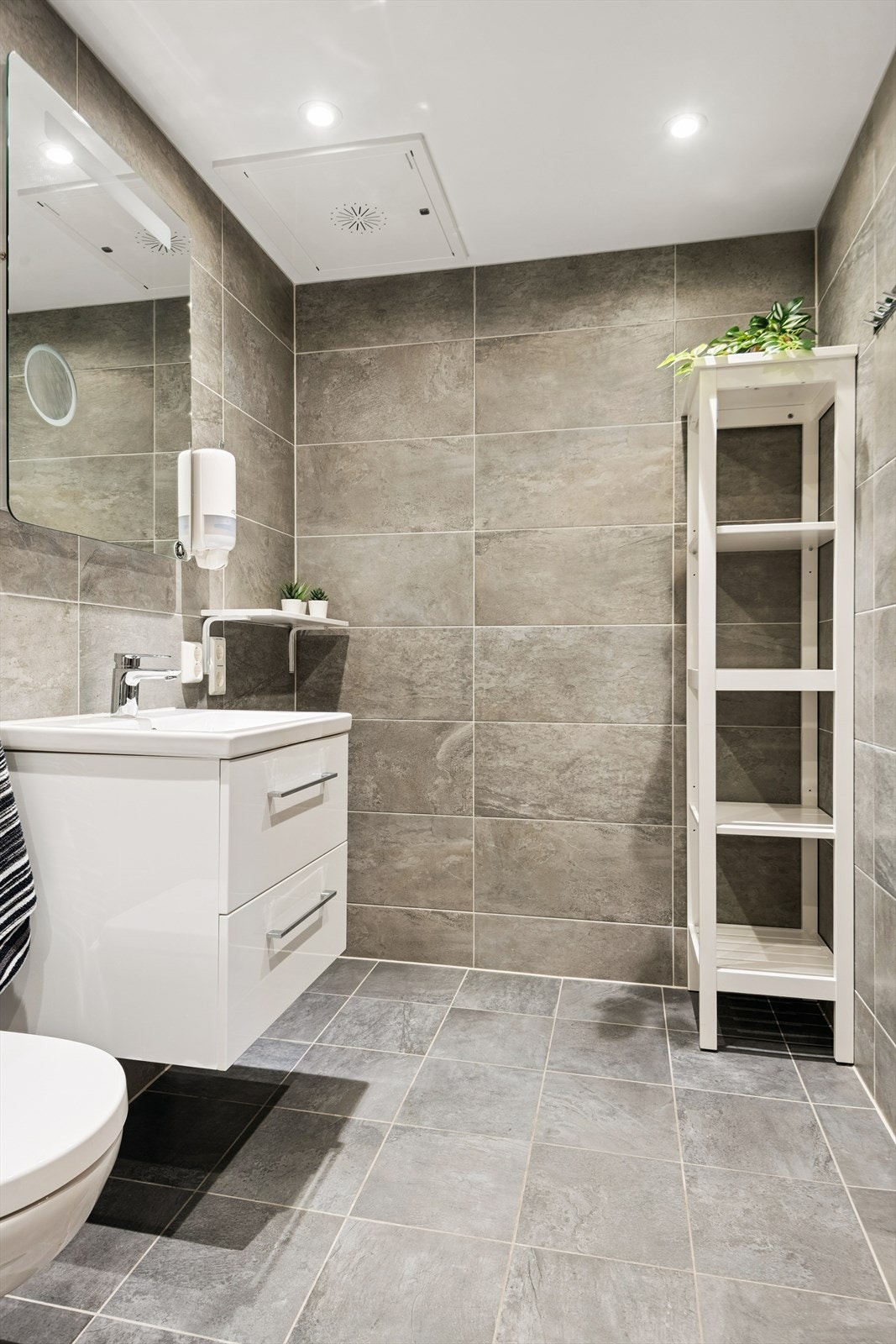 Badet har flislagte overflater og en vegghengt servantinnredning. Galleribilde