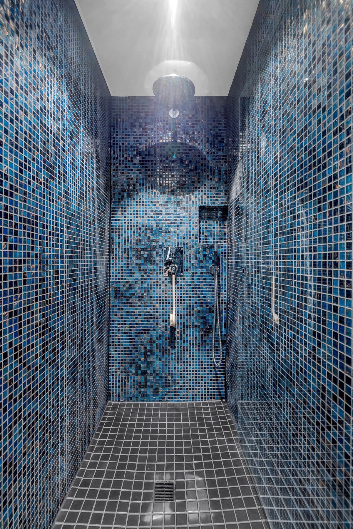 Stor dusjnisje med skjulte rør for vann, samt to-hodet dusjarmatur med håndholdt- og regnfallsdusj. Galleribilde