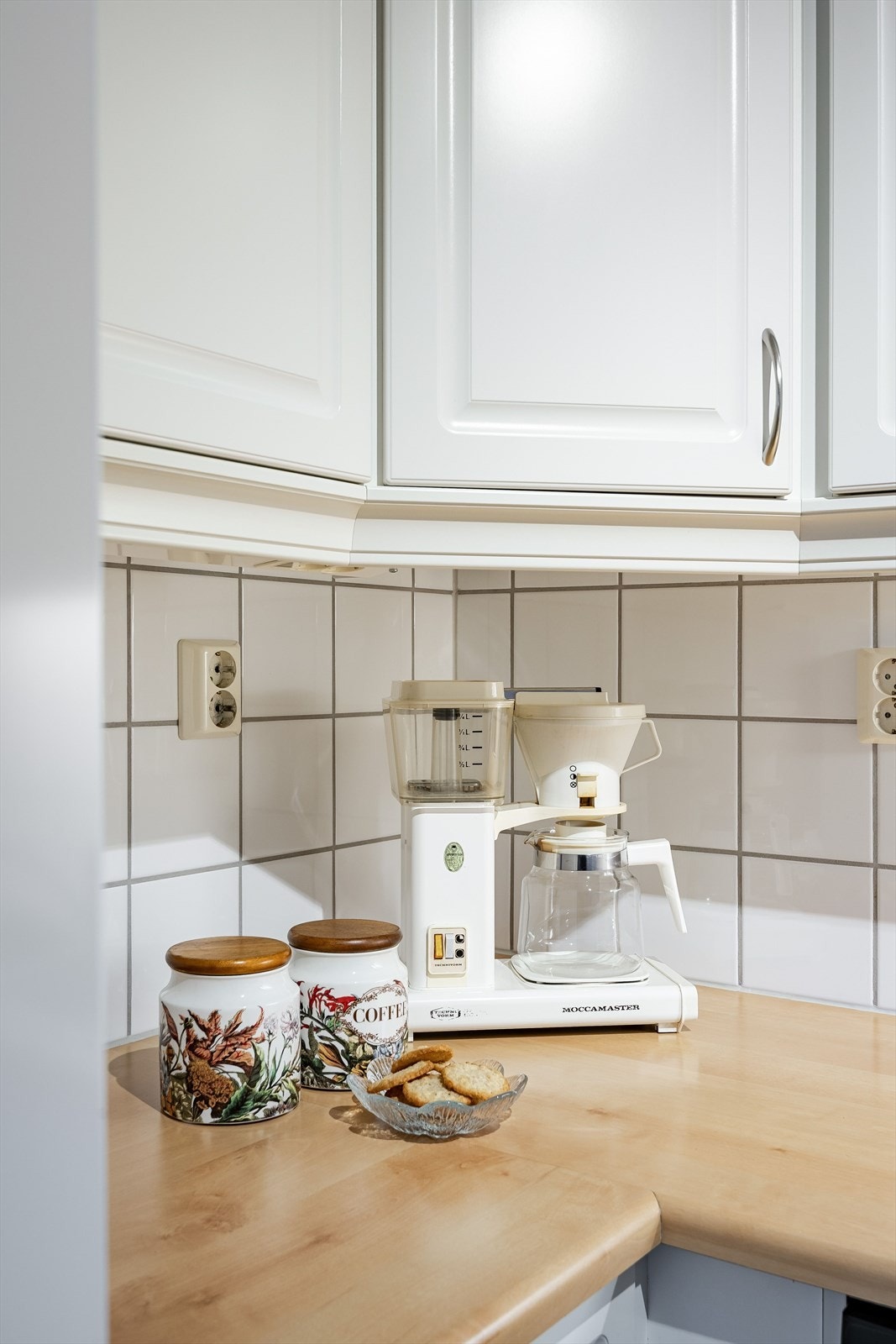 Kjøkkenet har hvite fliser i benkerygg og rikelig med stikkontakter for belysning. Galleribilde