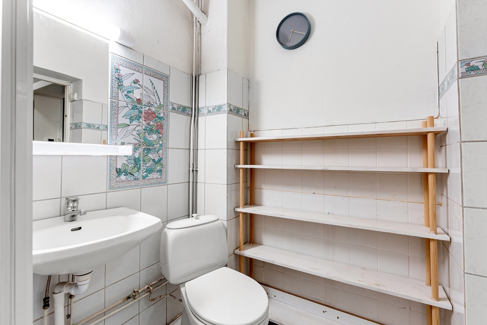 Det er hylle, speil og overbelysning med stikkontakt plassert på vegg over servant. Galleribilde