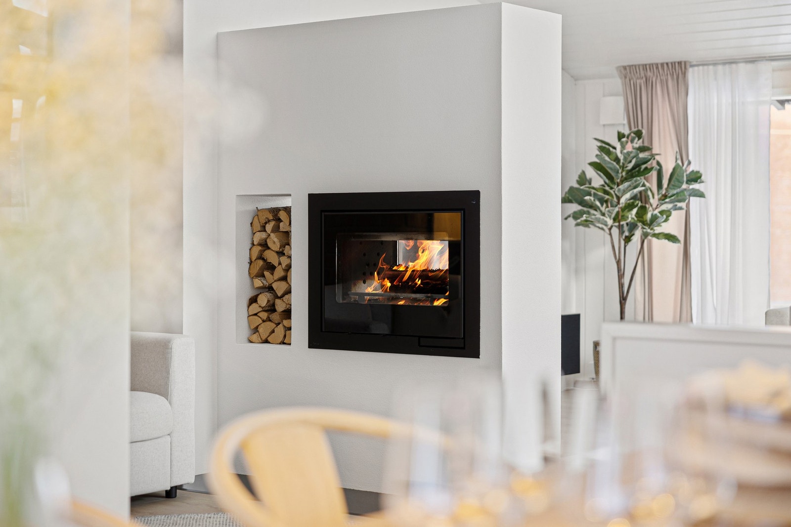 Boligen varmes effektivt opp av en moderne vedovn og varmepumpe i trappeløpet. Den integrerte vedhyllen gir peisløsningen et unikt og stilrent uttrykk, samtidig som den tilfører en dekorativ detalj med naturlige materialer. Galleribilde