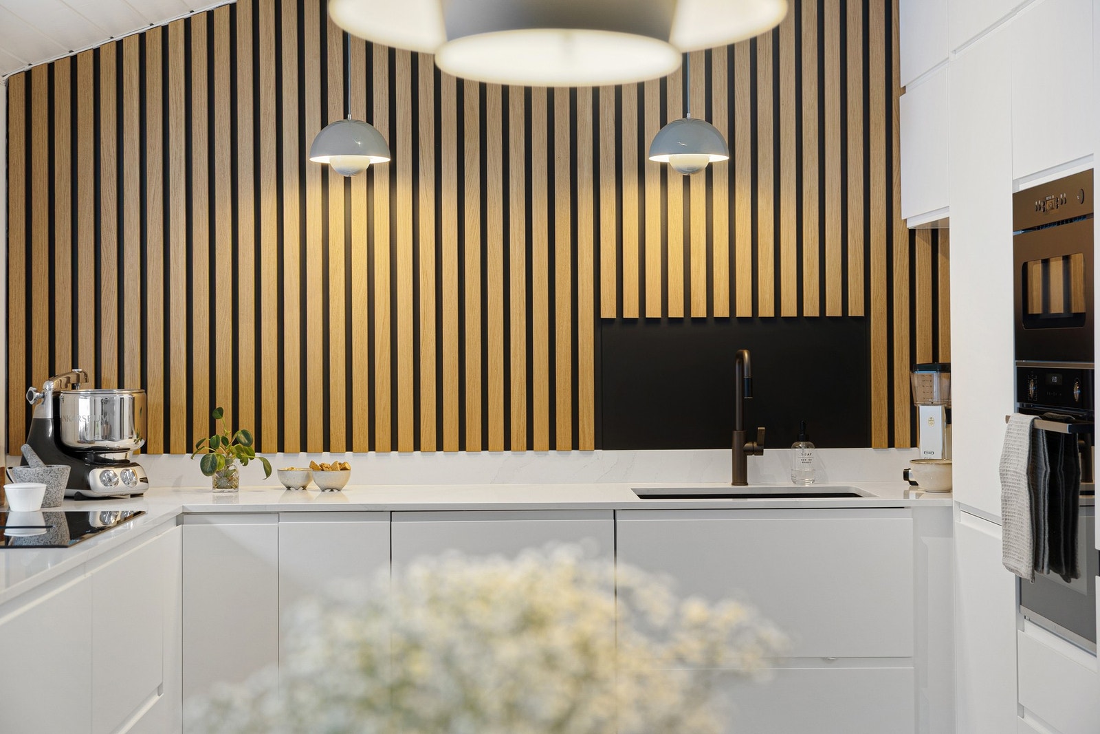 Dekorativ spilevegg og gjennomgående, sorte detaljer gir kjøkkenet et helhetlig uttrykk. Galleribilde