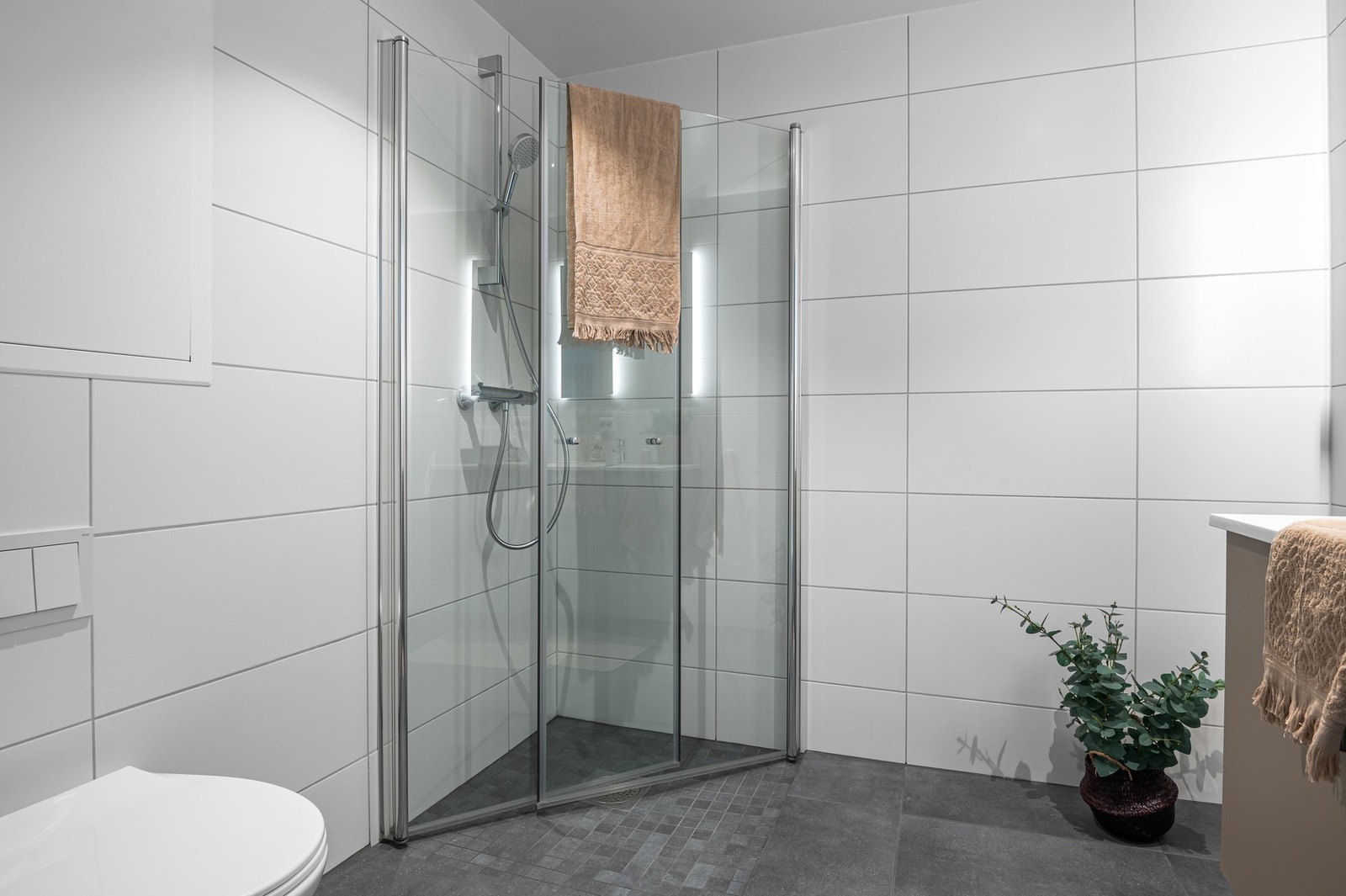 Badet er utstyrt med vegghengt toalett, dusjhjørne med innfellbare glassdører, opplegg til vaskemaskin, servant og servantskap. Galleribilde