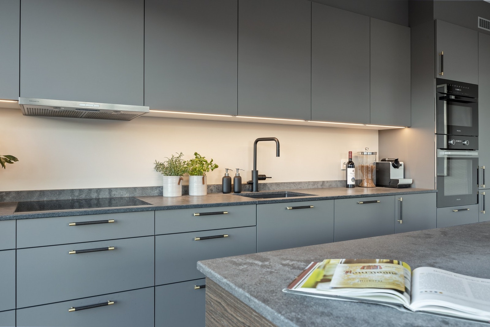 Moderne kjøkkeninnredning med integrerte hvitevarer og benkeplate i stein. Galleribilde