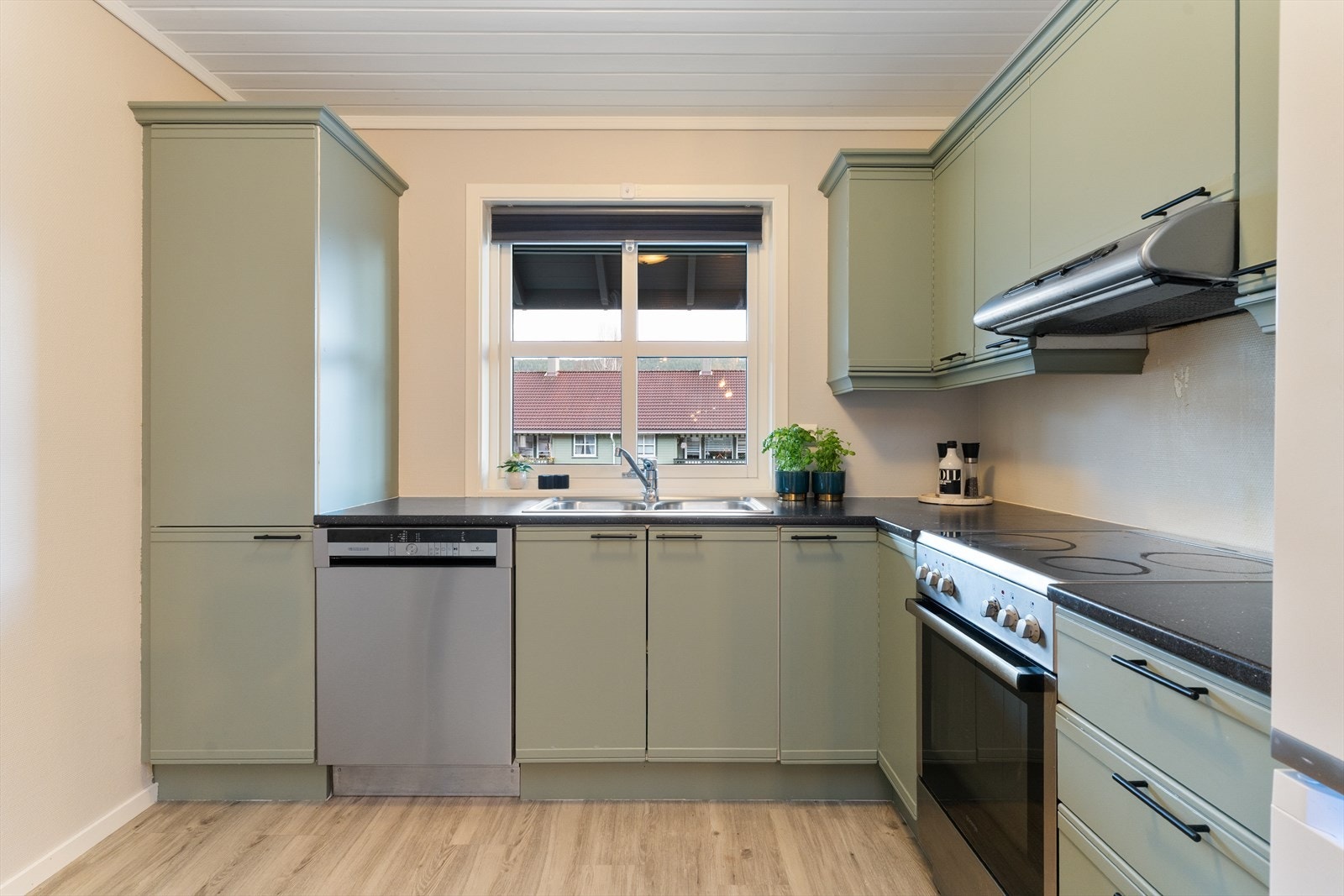 Kjøkkeninnredningen er malt i en behagelig grønnfarge. Laminat benkeplate med nedfelt vask og plass til komfyr. Galleribilde