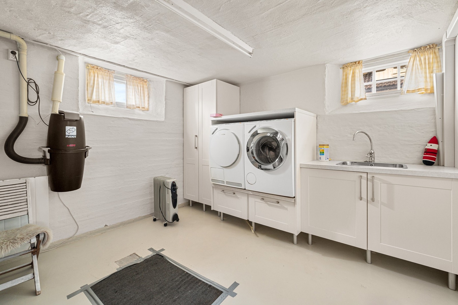 Romslig vaskerom med praktisk arbeidsbenk, oppbevaringsplass og plass til både vaskemaskin og tørketrommel. Galleribilde