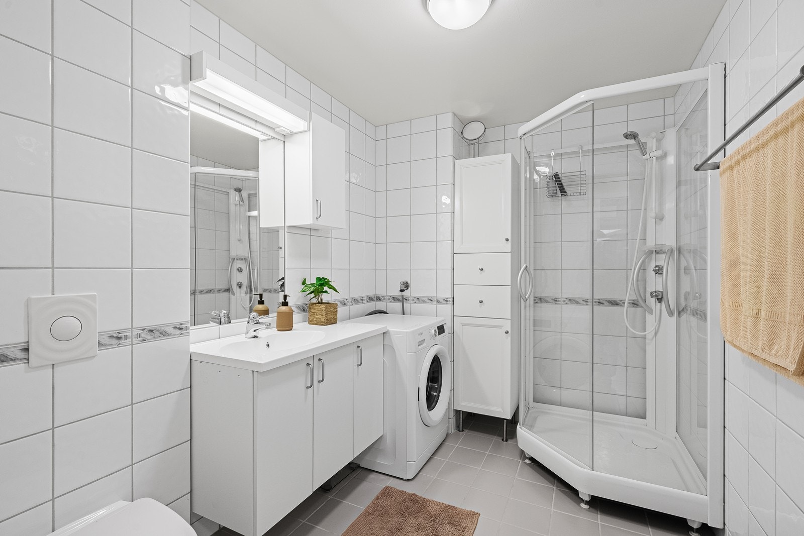 Badet har nedfelt servant, veggmontert toalett, dusjkabinett og opplegg for vaskemaskin. Galleribilde