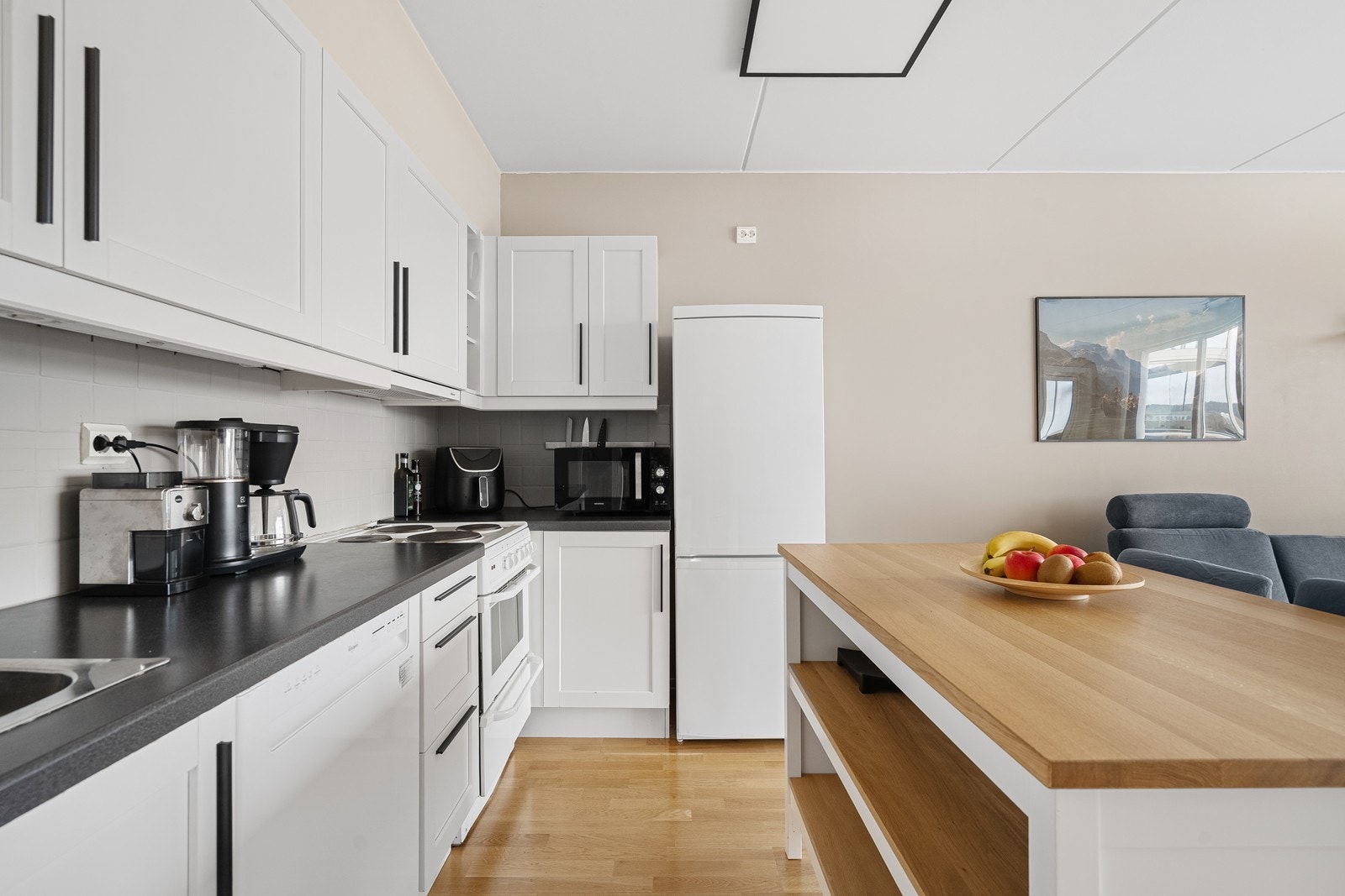 Kjøkkenet har hvit, profilert innredning og en grå laminert benkeplate. Galleribilde