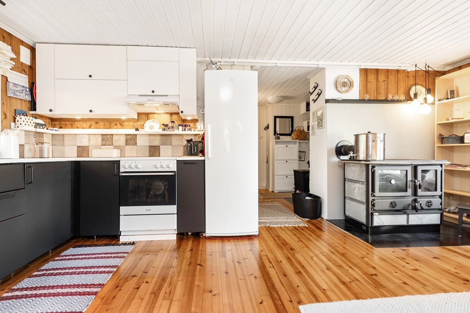 Kjøkkenet har moderne hvitevarer og vedovn/komfyr. Lyse overflater og tregulv gir en varm atmosfære. Galleribilde