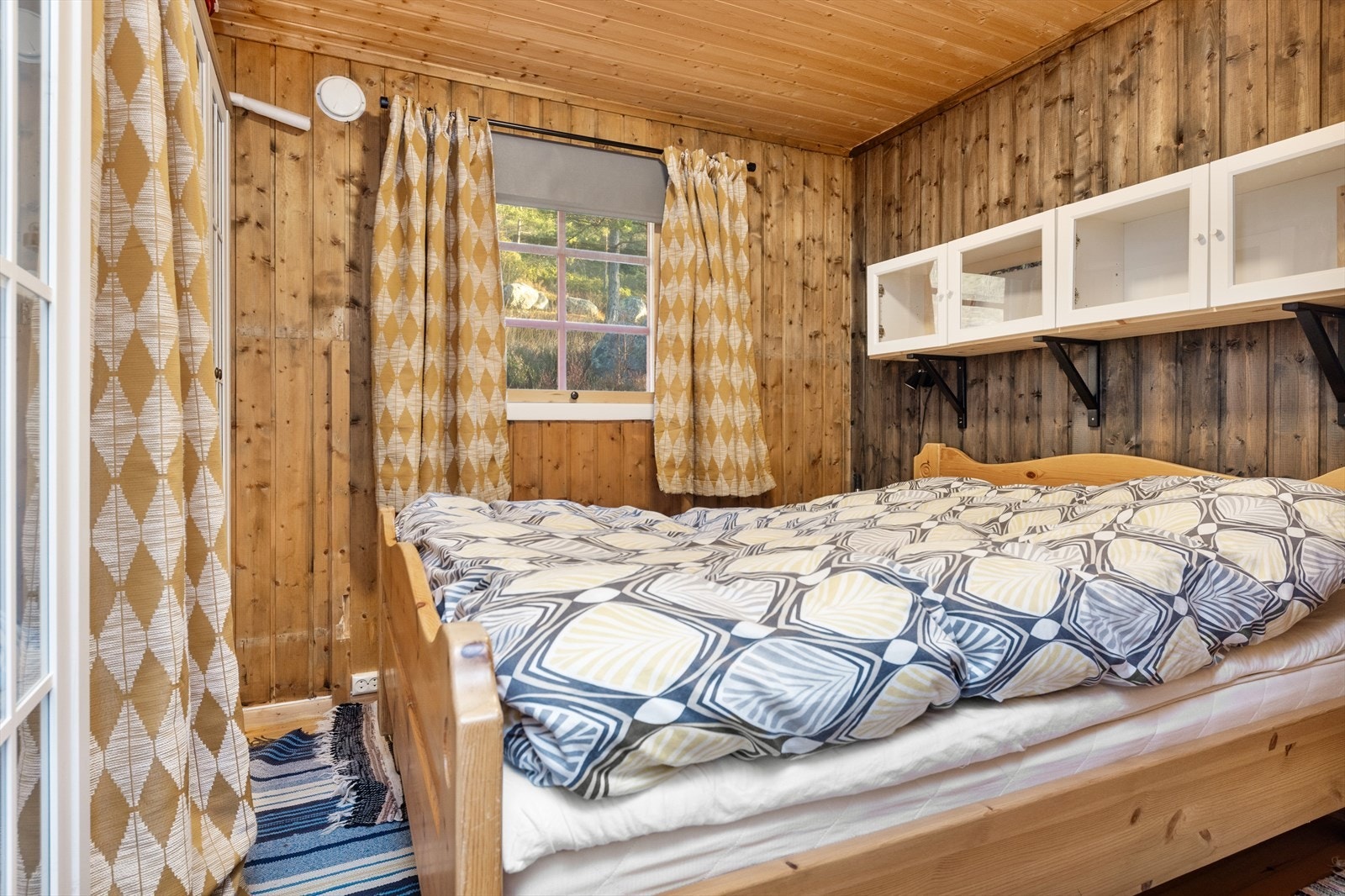 Soverom med trepanel og store vinduer som slipper inn naturlig lys. Galleribilde