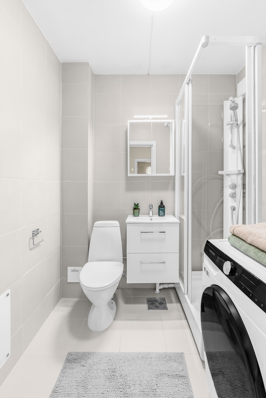 Pent og funksjonelt bad med helflisede overflater som gir et stilrent og tidløst uttrykk. Galleribilde