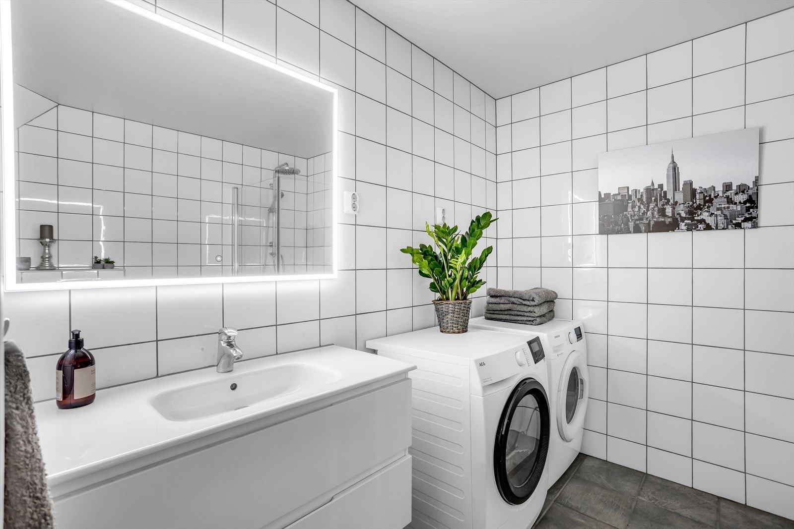 Her er det varmekabler i gulvet, belyst speil og praktisk opplegg for vaskemaskin. Galleribilde