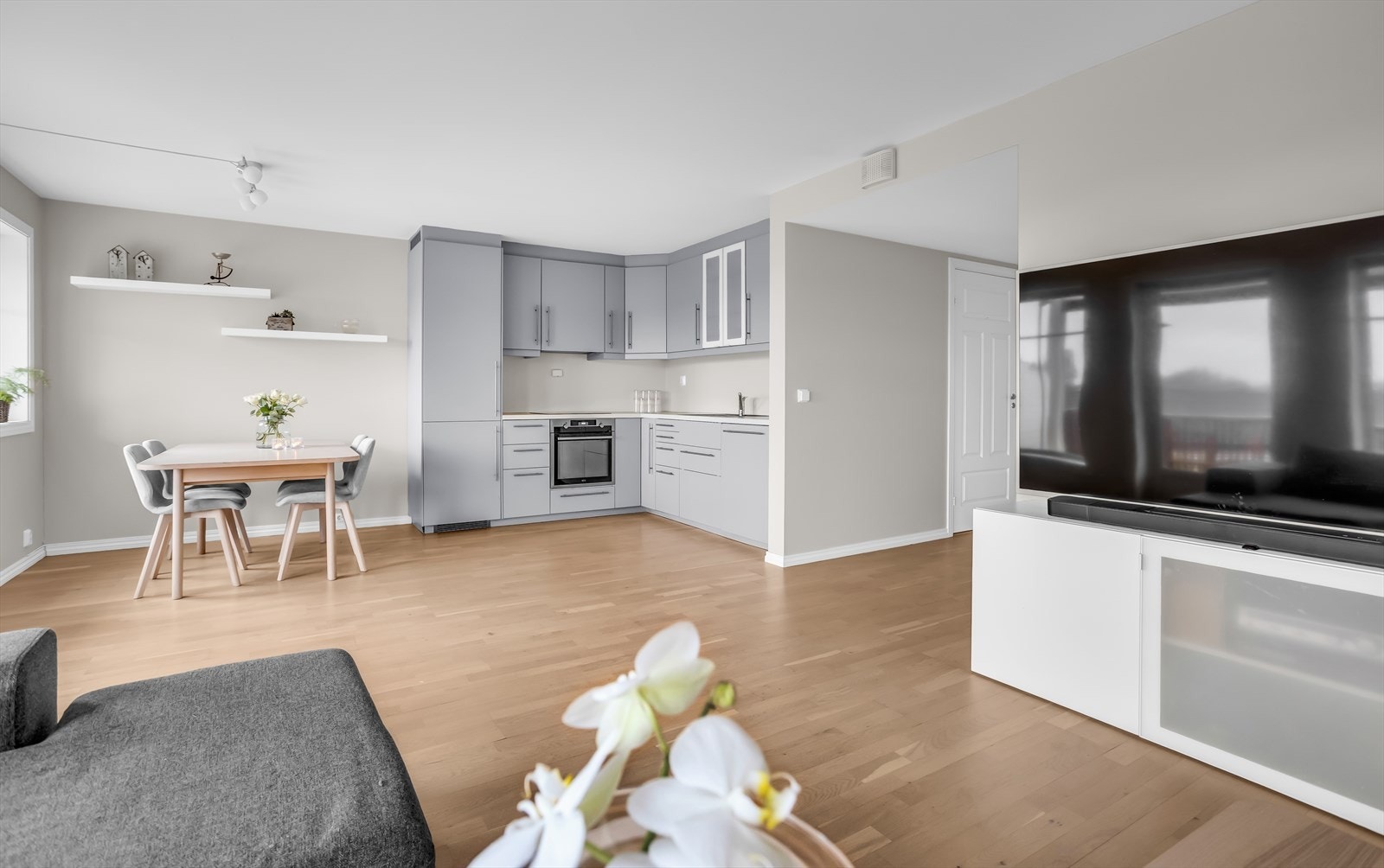 Pen IKEA-kjøkkeninnredning med grå, glatte fronter og rikelig med skapplass. Galleribilde