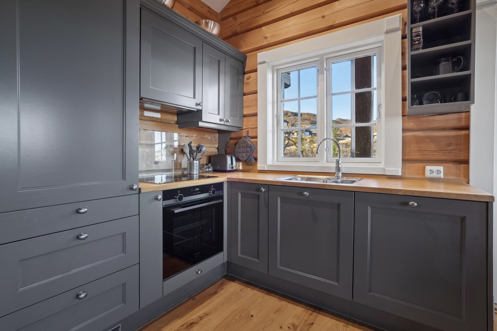 Stilren kjøkkeninnredning med integrerte hvitevarer og heltre benkeplate med nedfelt oppvaskbeslag. Galleribilde