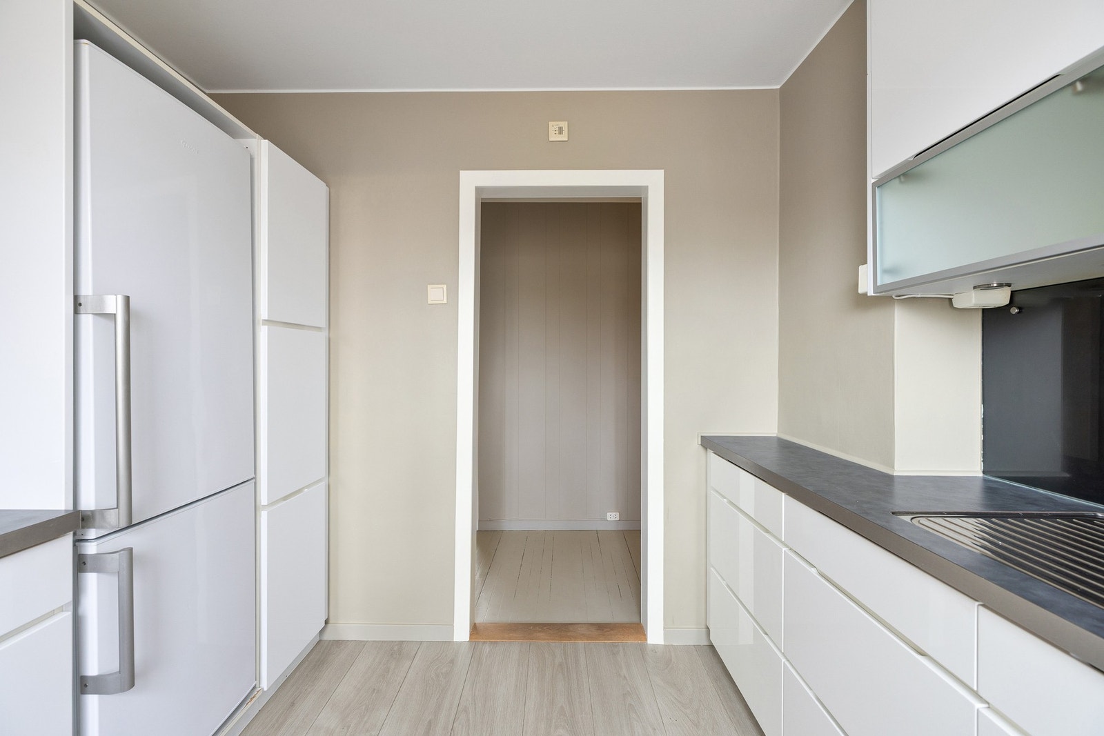 Videre er kjøkkenet utstyrt med integrerte hvitevarer som platetopp og komfyr Galleribilde