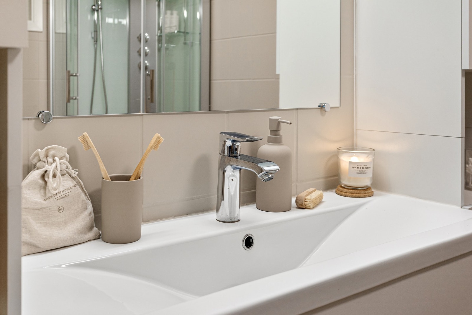 Badet er innredet med dusjkabinett, gulvmontert toalett, servantinnredning med slette fronter, speil og veggskap. Galleribilde