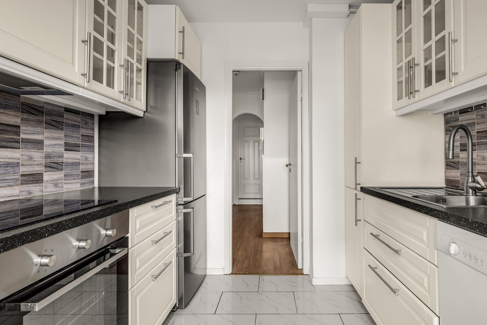 Kjøkkenet er utstyrt med nedfelt induksjonsplatetopp, ventilator under overskap, oppvaskmaskin under benk, frittstående kjøleskap med frysedel samt komfyrvakt. Galleribilde