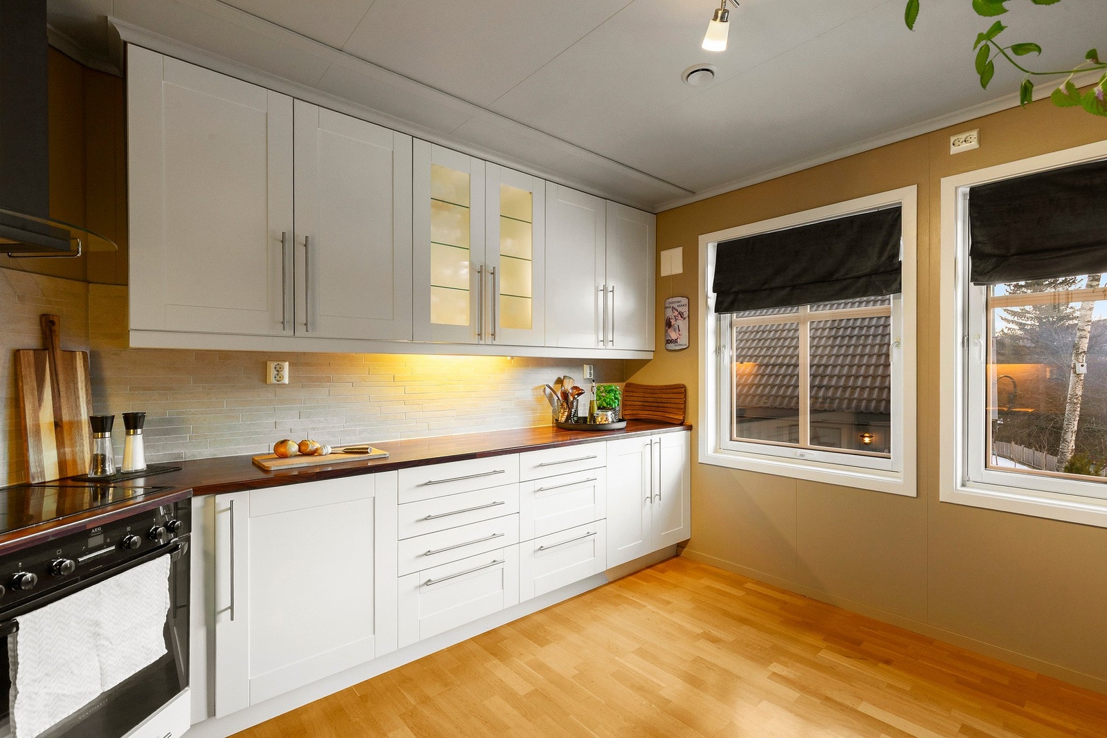 Stilren kjøkkeninnredning med integrert stekovn, platetopp og kjøl/fryseskap. Det er mekanisk avtrekksvifte over stekesonen, og opplegg for oppvaskmaskin. Galleribilde