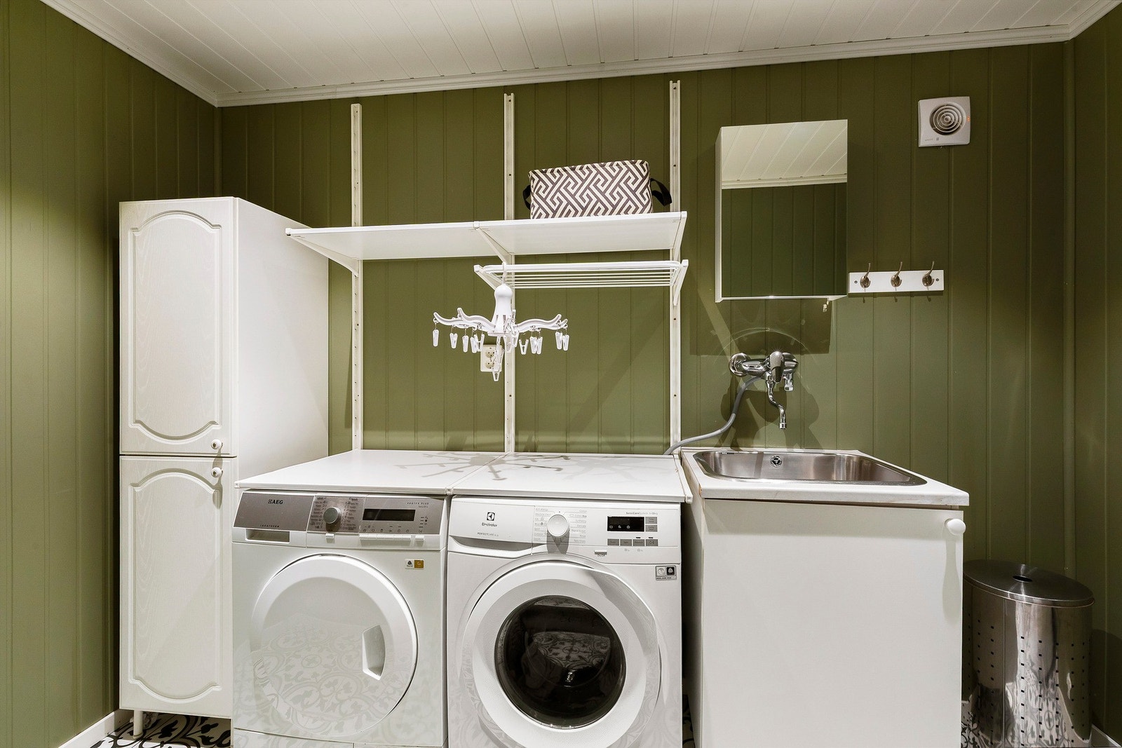 Praktisk vaskerom med opplegg for vaskemaskin, skyllekum, stoppekran, rørfordelingsskap og bereder. Mekanisk avtrekk. Stilige fliser på gulv, gulvvarme og malte panelplater på vegg. Panel og downlights i himling. Galleribilde