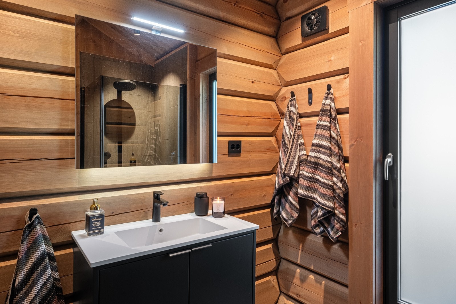 Badet har stilfull spotbelysning og skråhimling som gir god takhøyde. Baderomsinnredningen er fra Brusveen Snekkerverksted AS og består av heldekkende servant med sort blandebatteri og underskap med glatte fronter. Galleribilde