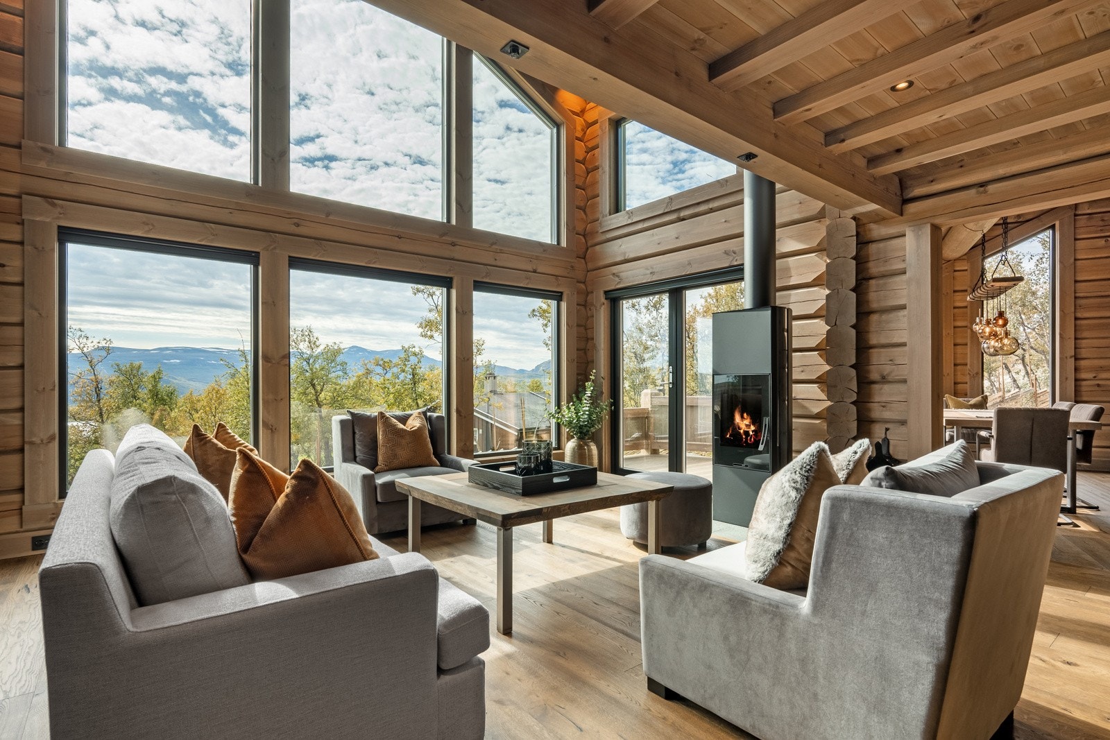 Stuen har lekker eikeparkett på gulv, massive tømmervegger og paneltak beiset i en lun farge. I himlingen er det flott belysning, og de store vindusflatene med soldemping, gir behagelige lysforhold og lar den vakre utsikten bli en del av rommet. Galleribilde