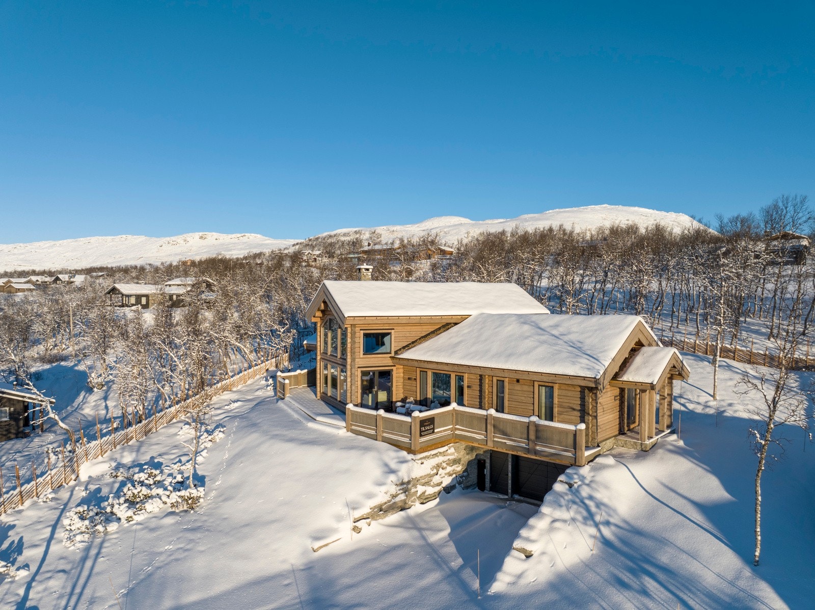 Bilen kan kjøres helt frem til hytteveggen, og det er rikelig med parkering i både romslig garasje og på gruslagt gårdsplass. Hytta har praktisk inngang både fra første etasje og direkte fra garasjen som ligger i kjelleretasjen. Galleribilde