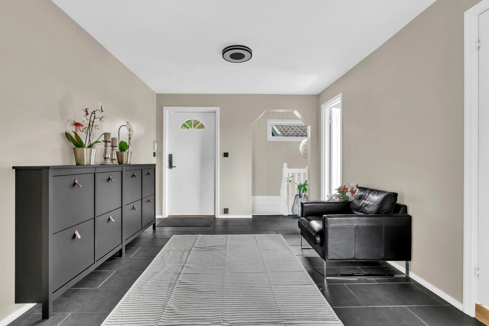 Boligen byr på en stor entré med store svarte fliser på gulv og lyse overflater. Videre er det god plass til garderobeskap eller andre oppbevaringsmuligheter for både ytterklær og sko. Galleribilde