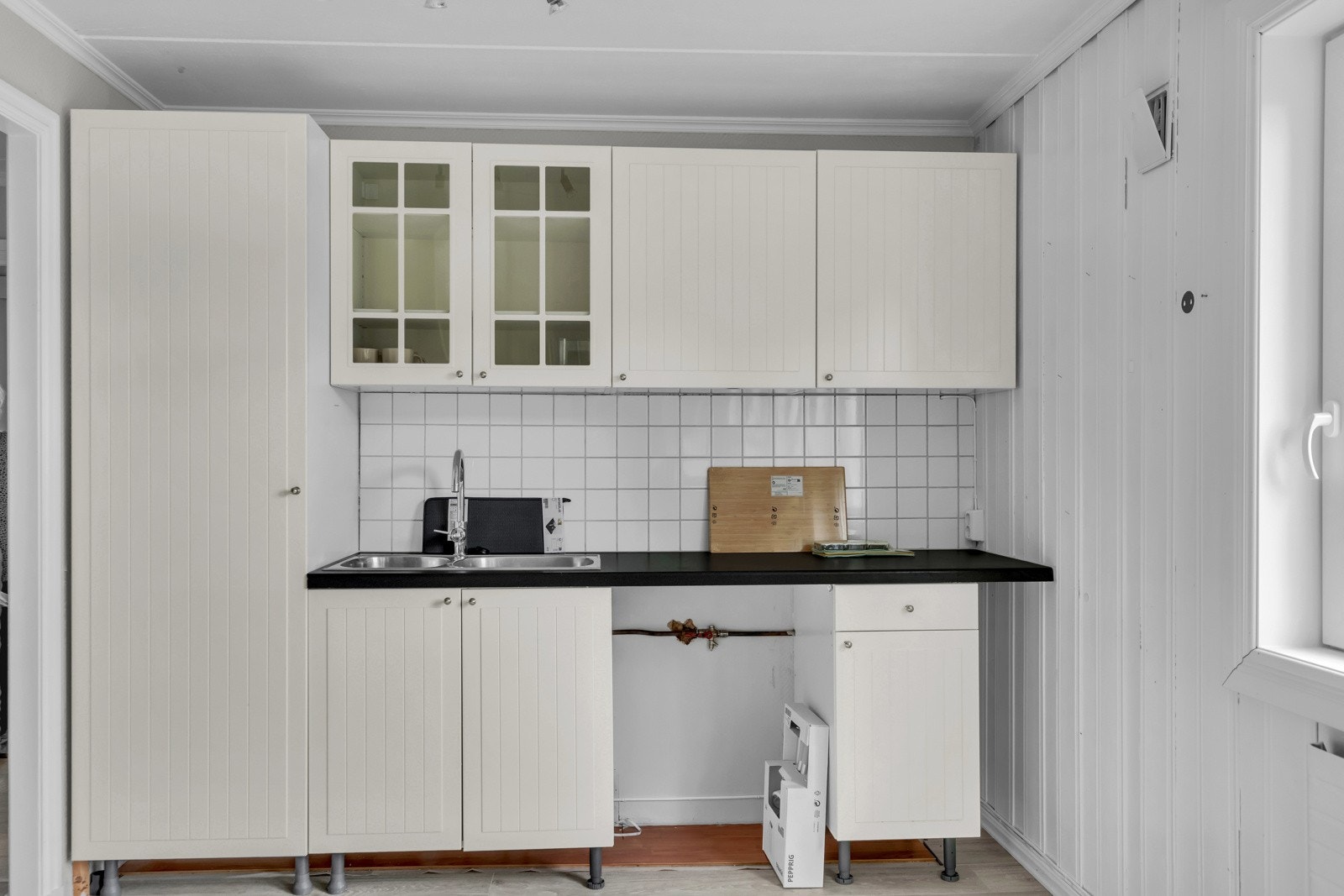 Kjøkkenet består av lyse profilerte fronter, vitrineskap, laminert benkeplate med oppvaskkum i rustfritt stål, opplegg for vaskemaskin samt avsatt plass til komfyr. Galleribilde