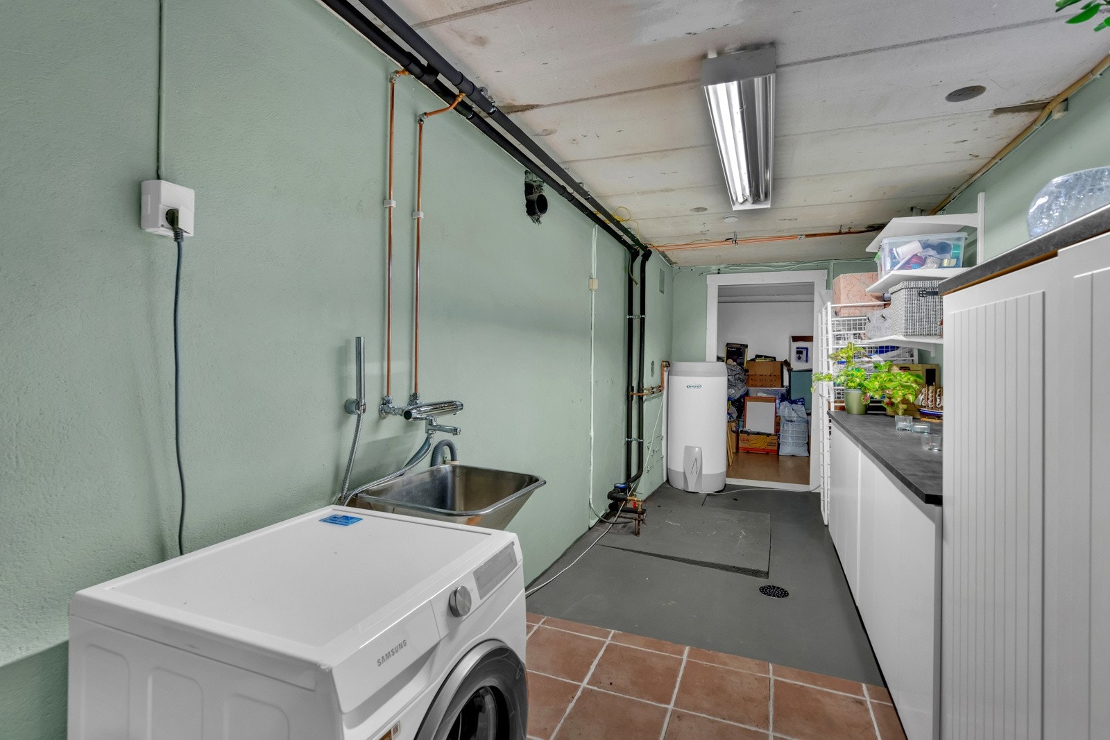 Vaskerommet har innredning bestående av benkeskap med laminert arbeidsbenk, skyllekum, varmtvannsbereder, vegghengt hyllesystem samt opplegg for vaskemaskin. Galleribilde