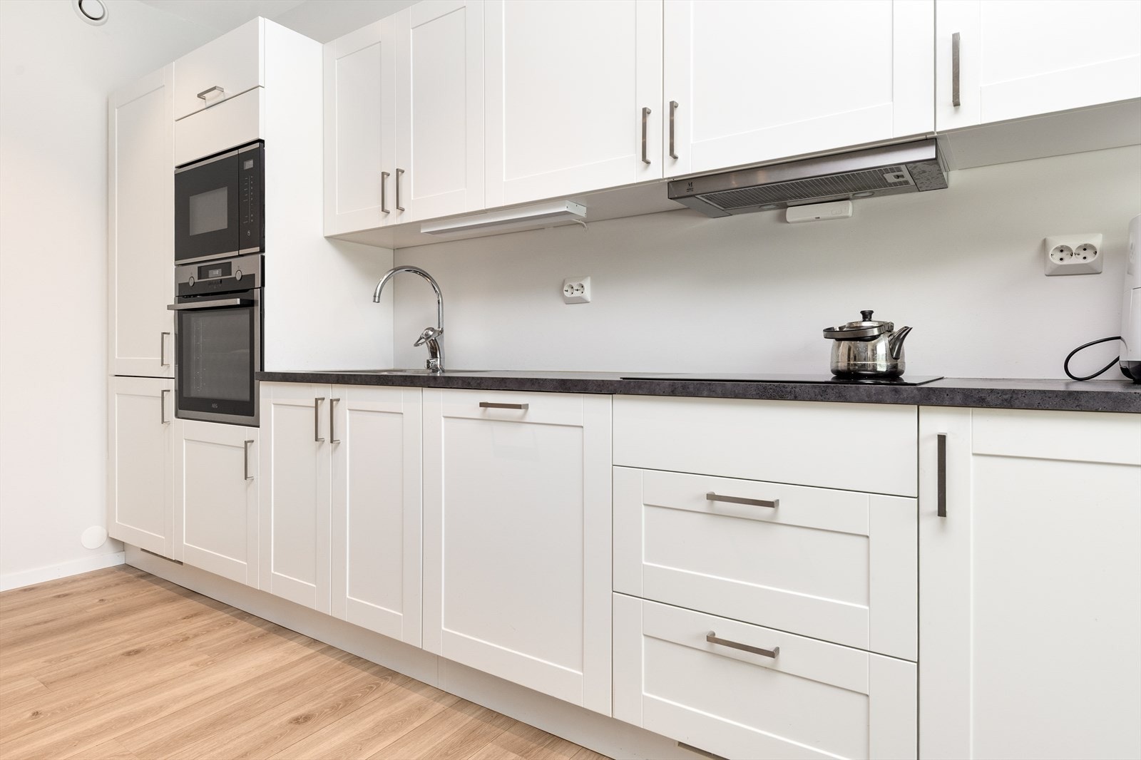 Lyst kjøkken med profilerte fronter og integrerte hvitevarer. Galleribilde