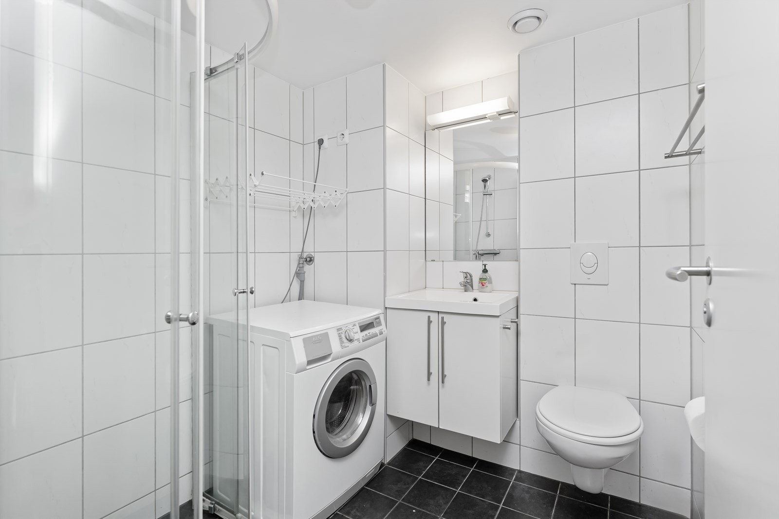 Her har du baderomsinnredning med nedfelt vask, toalett, dusjhjørne og vaskemaskin. Galleribilde