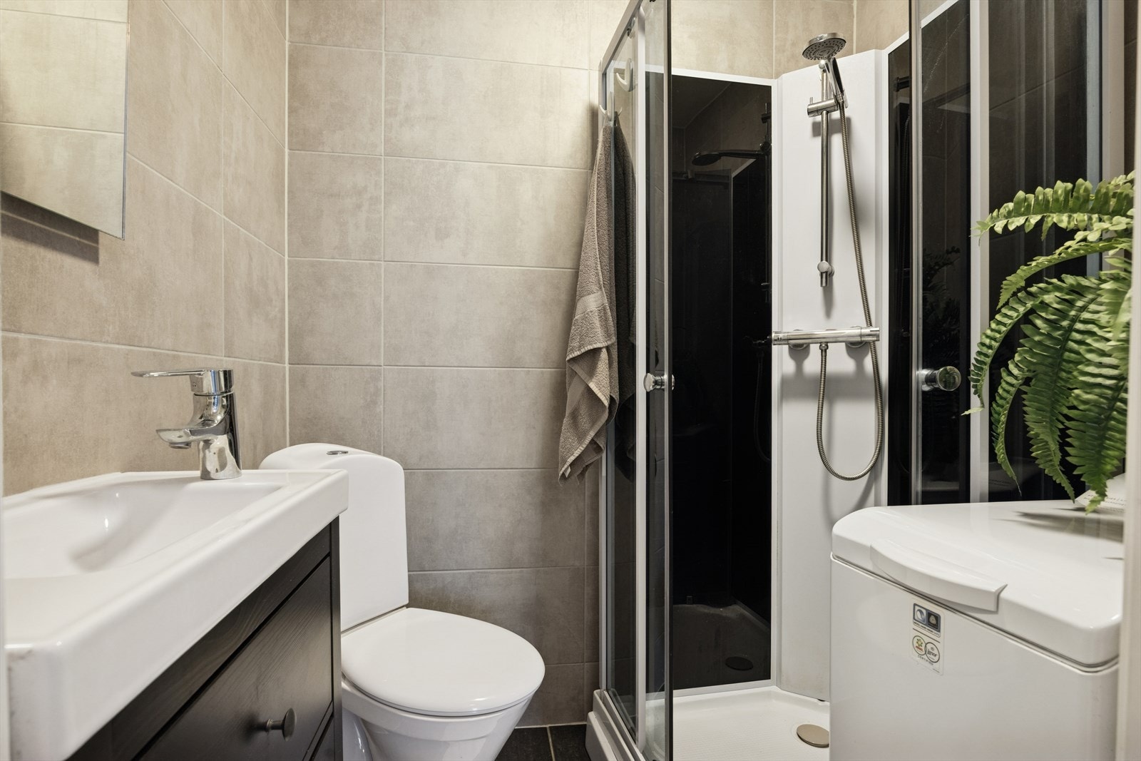 Baderom med flis på gulv,vegger og malt slett himling. Galleribilde