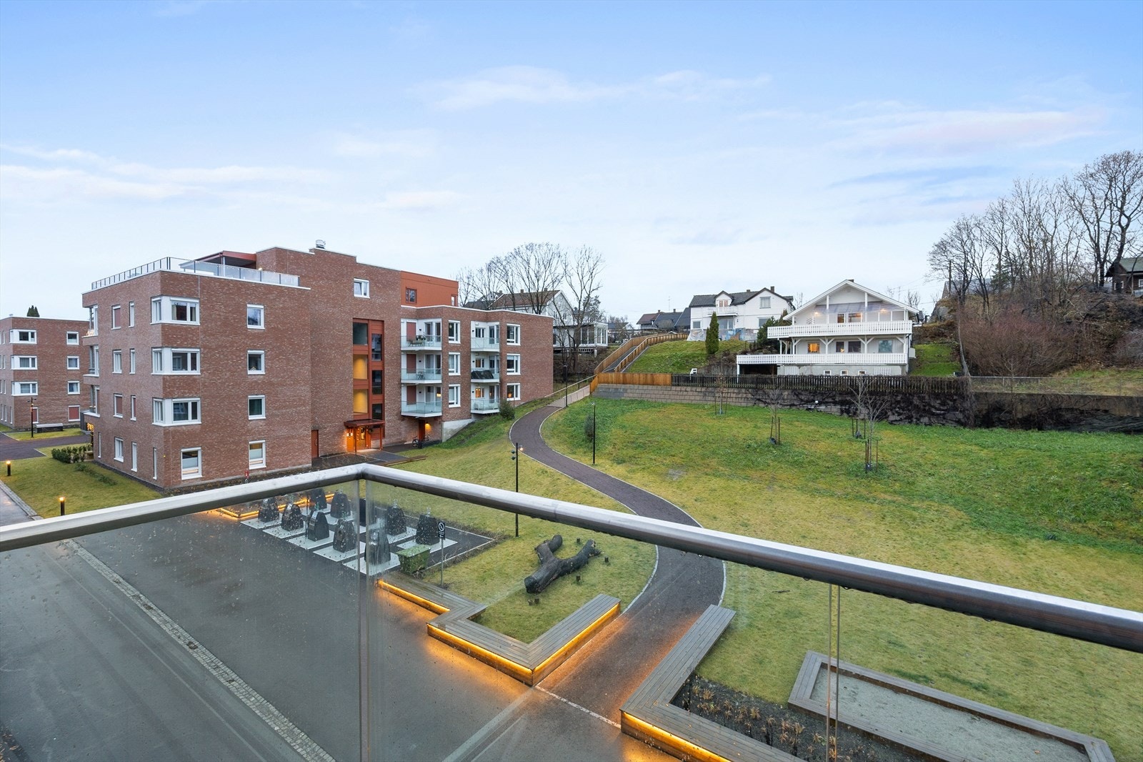 Utsikt fra balkongen mot det grønne tunet på utsiden. Galleribilde