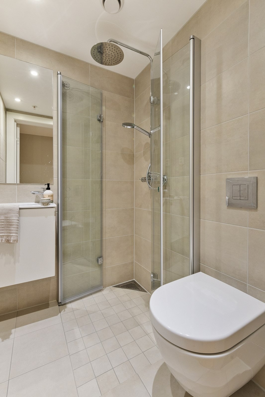 Dusjhjørne på ekstrabadet med innfellbare dusjvegger, vegghengt toalett og servant - stilrent og funksjonelt. Galleribilde