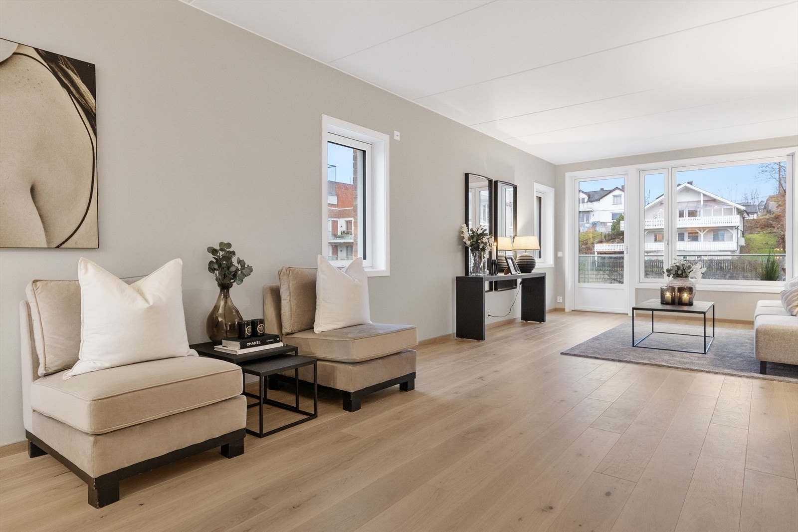 Stuen sett fra spisestuen. Store vinduer gir flott utsyn og generøst dagslys. De gjennomgående gulvene binder hele oppholdsarealet sammen til én helhetlig og moderne leilighet. Galleribilde