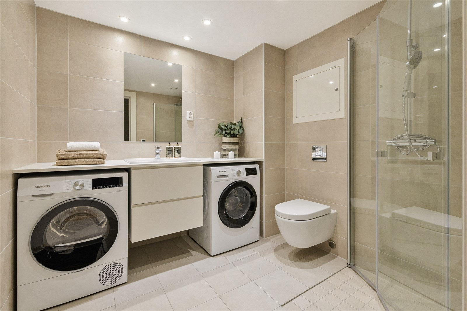 Badet har heldekkende benkeplate over vasken, som kan romme vaskemaskin og tørketrommel på en delikat og ryddig måte. Galleribilde