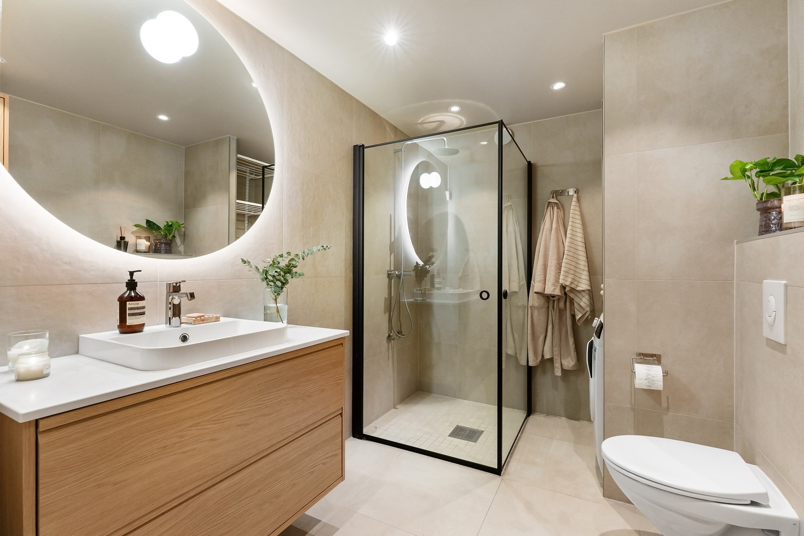 Innredningen i eik, det runde speilet med belysning og dusjhjørnet skaper et moderne uttrykk. Galleribilde