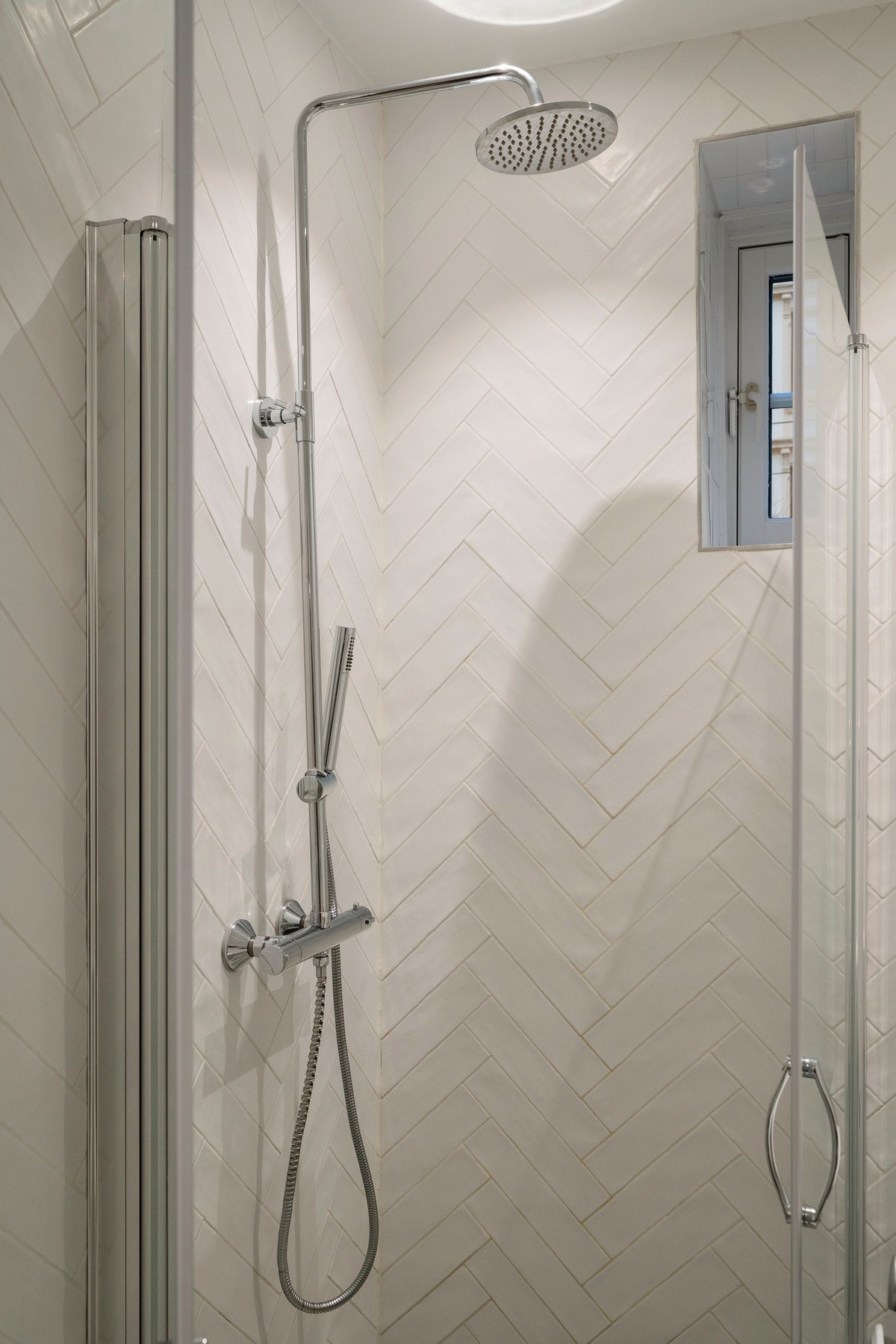 Romslig dusjhjørne med innfellbare dusjvegger og stilren regnfallsdusj med hånddusj. Galleribilde