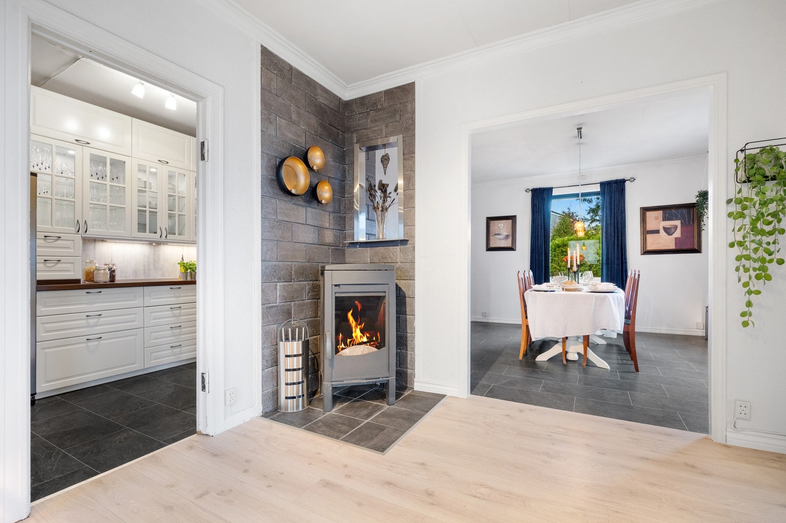 Åpen løsning mellom stue, kjøkken og spisestue. Moderne vedovn plassert "mellom" rommene Galleribilde