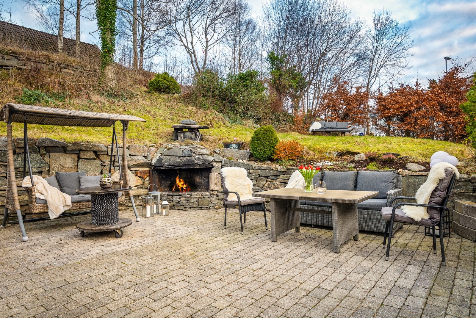 Opparbeidet uteplass med pene forstøtningsmurer og utendørs peis Galleribilde