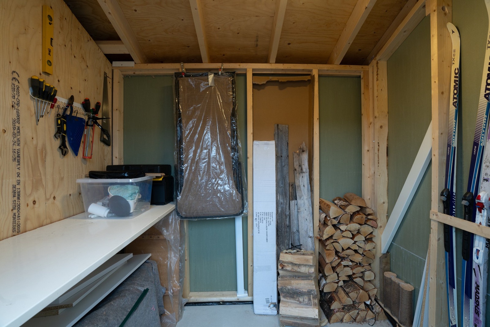 Utvendig bod med praktisk benkeplate og gode oppbevaringsmuligheter for ved, ski og utemøbler Galleribilde