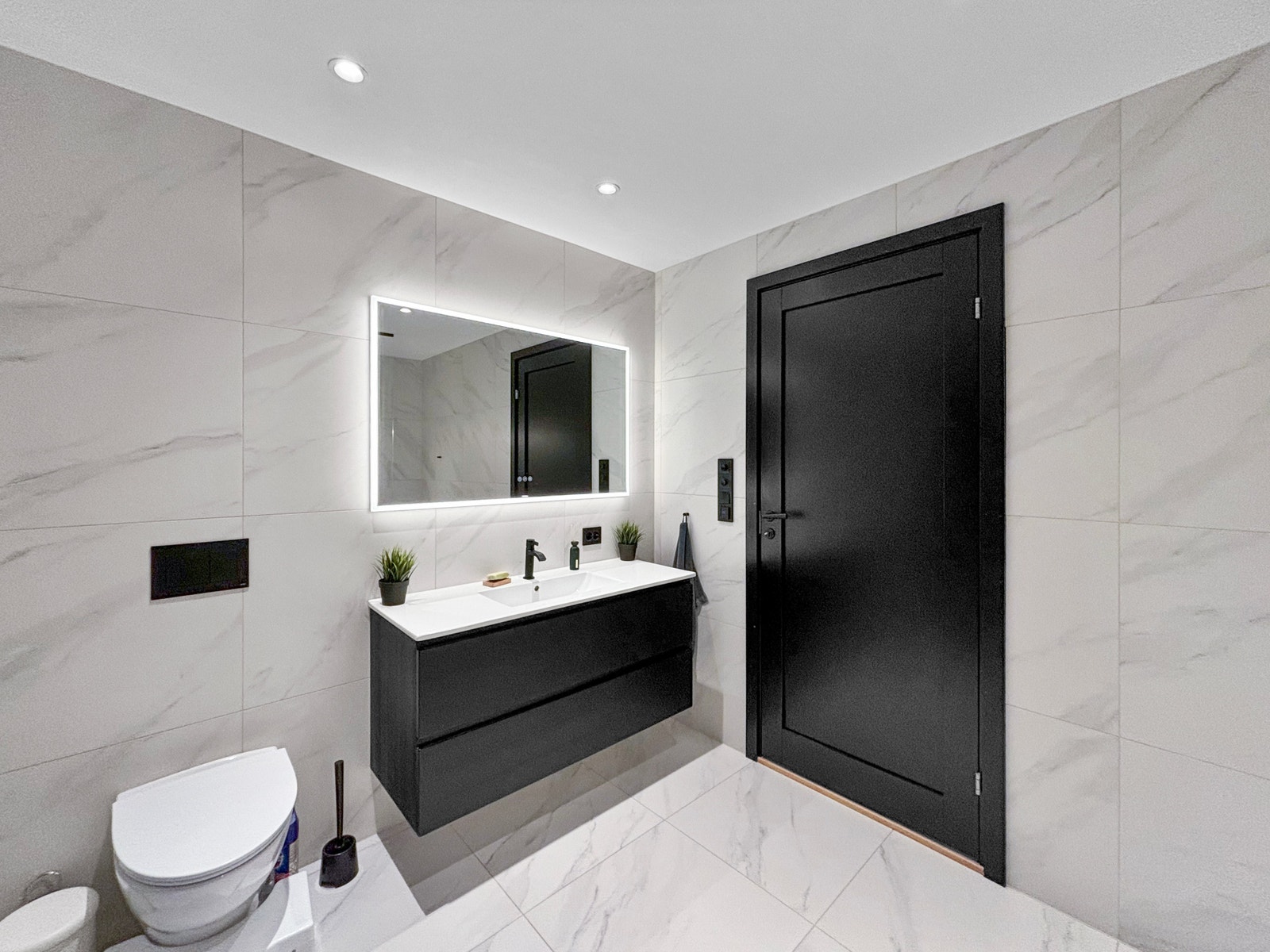 Badet er stilrent med lyse fliser og svarte detaljer. Galleribilde